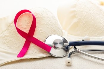 Healthcare, medicine and breast cancer awareness concept. Closeup pink ribbon and stethoscope on female bra.
