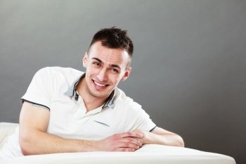 Home, leisure and happiness concept. Young handsome smiling man relaxing on couch