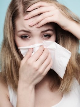 Flu cold or allergy symptom. Sick woman girl with fever sneezing in tissue on blue. Health care.