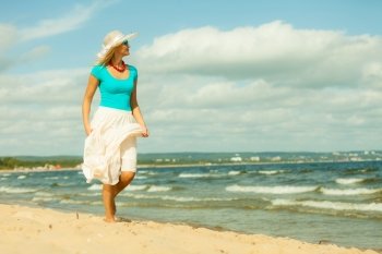 Holidays, vacation travel and freedom concept. Beautiful girl in summer clothing hat running on beach. Young woman having fun relaxing on the sea coast.