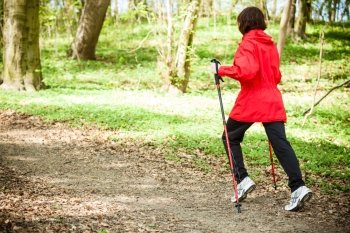 Nordic walking. Woman hiking in the forest or park. Active and healthy lifestyle.