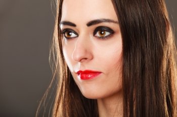 Closeup portrait beautiful young woman long straight hair dark makeup red lips on gray