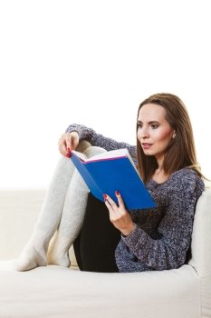 Leisure, education, literature and home concept. Woman sitting on couch reading book at home