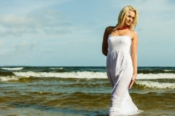 Holidays, vacation travel and freedom concept. Beautiful girl in white dress walking on beach. Young woman relaxing on the sea coast.