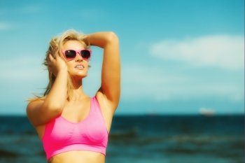 Holidays, summer active lifestyle concept. Attractive blonde fit fitness girl on beach. Young sporty woman relaxing on the sea coast.