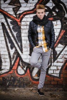 Full length of handsome stylish man outdoor in city setting, male model fashionable clothing against graffiti wall