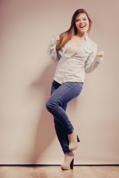 Happy woman wearing denim pants high heels. Girl in full length celebrating success clenching fist filtered photo