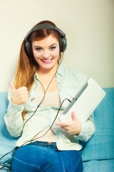 Modern technology leisure concept. Young attractive woman with headphones relaxing using tablet making thumb up hand sign gesture