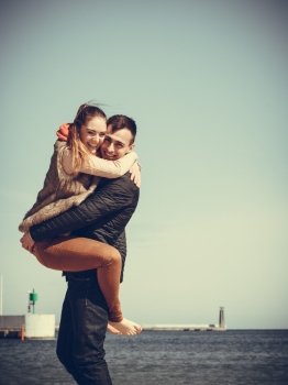 happy young romantic couple in love having fun on beach at sunny cold day