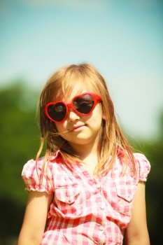 Summer vacation. Portrait of cute little girl kid child in red sunglasses in the shape of heart outdoor.