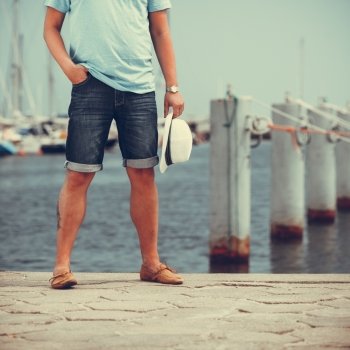 Closeup on man legs tourist on pier in port with yachts. Guy enjoying summer travel vacation by sea. Full length.