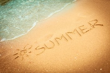 Holidays vacation concept. The word summer written in the sand on beach.