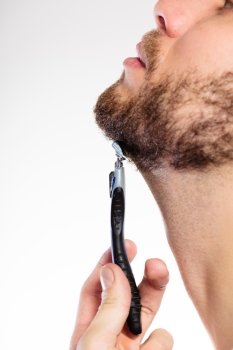Health beauty and skin care concept. Closeup part of male face. Young man guy styling beard holding disposable blue razor blade white background.