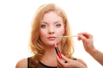 Cosmetic beauty procedures and makeover concept. Makeup artist applying lipstick with accessories tools to woman lips. Isolated studio shot