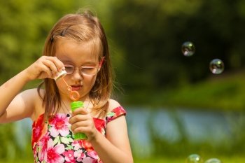 Little girl child blowing soap bubbles outdoor.. Little girl child blowing soap bubbles outdoor. Kid having fun in park. Happy and carefree childhood.