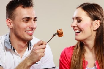 Smiling man feeding happy woman with cake.. Smiling man feeding happy woman with cake. Wife and husband eating caloric food.