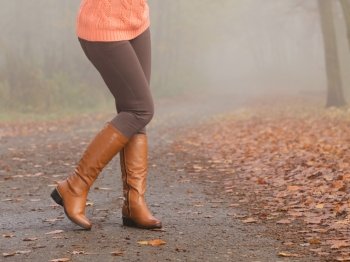 Closeup of woman legs in brown boots. Fall fashion. Closeup of woman legs in brown boots. Girl in autumn park forest. Fall winter fashion.