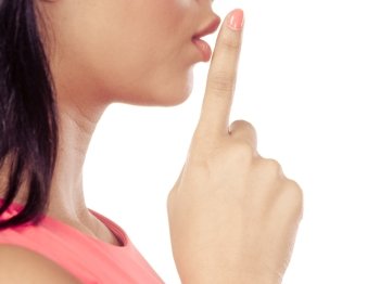 Woman with finger on lips showing silence gesture.. Closeup of mixed race woman girl with finger on lips showing hand quiet silence sign gesture isolated on white.