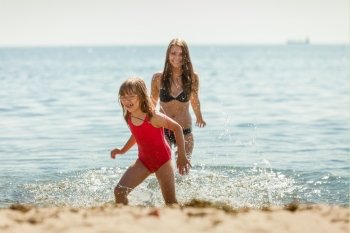 Little girl kid and woman mother in sea water. Fun. Little girl child and mother having fun in ocean. Kid and woman bathing in sea splashing water. Summer vacation holiday relax.