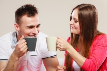 Happiness and healthy relationship concept. Attractive couple drinking tea or coffee together, man and woman holding mugs with hot beverage