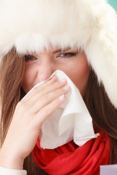 Sick woman sneezing in tissue. Winter cold.. Sick woman in fur hat sneezing in tissue. Ill girl caught winter cold flu in studio on green.