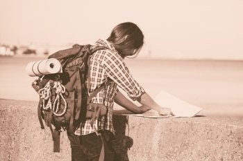 Man hiker backpacker with backpack by seaside reading map searching looking for direction guide. Adventure, tourism active lifestyle. Young long haired guy tramping