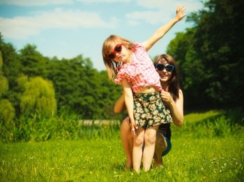Summer vacation. Little girl kid child daughter playing with mother in flying on the meadow or in the park.