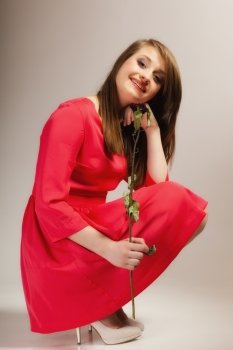 Beautiful fashion woman in full length teen girl in red gown with dry rose on gray background
