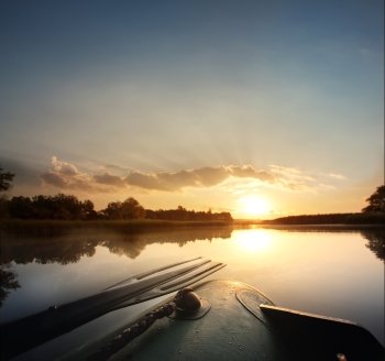 Beautiful dawn morning in an inflatable boat with a paddle in calm water