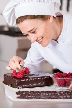 Pastry chef in the kitchen decorating a cake of chocolate